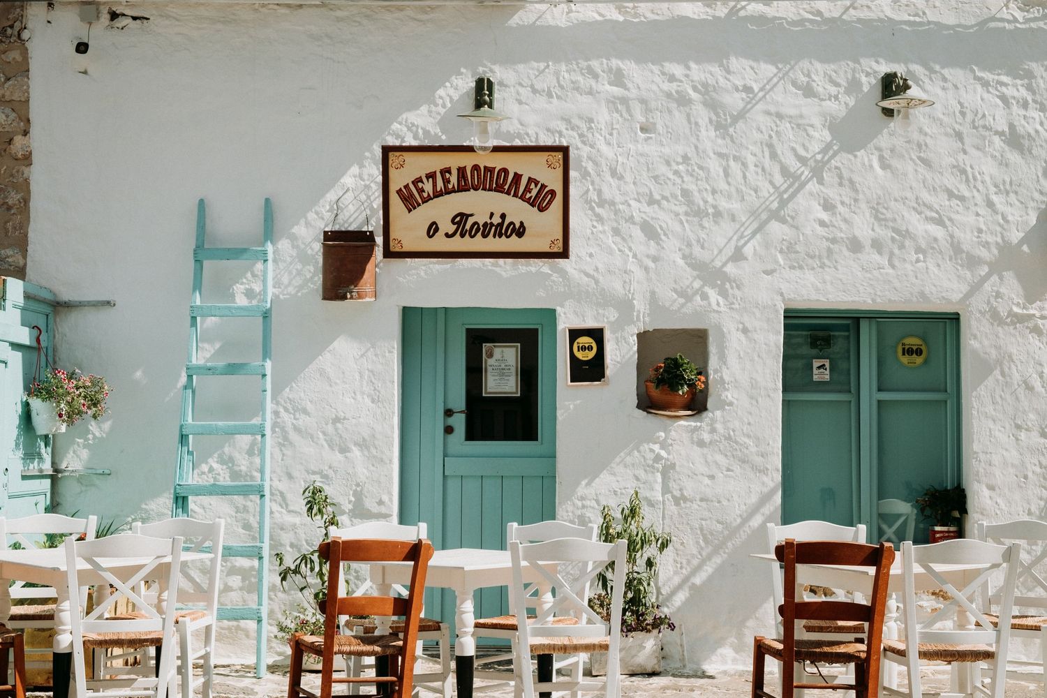 Traditional Greek taverna with turquoise doors and white walls showcasing rustic outdoor seating arrangements.