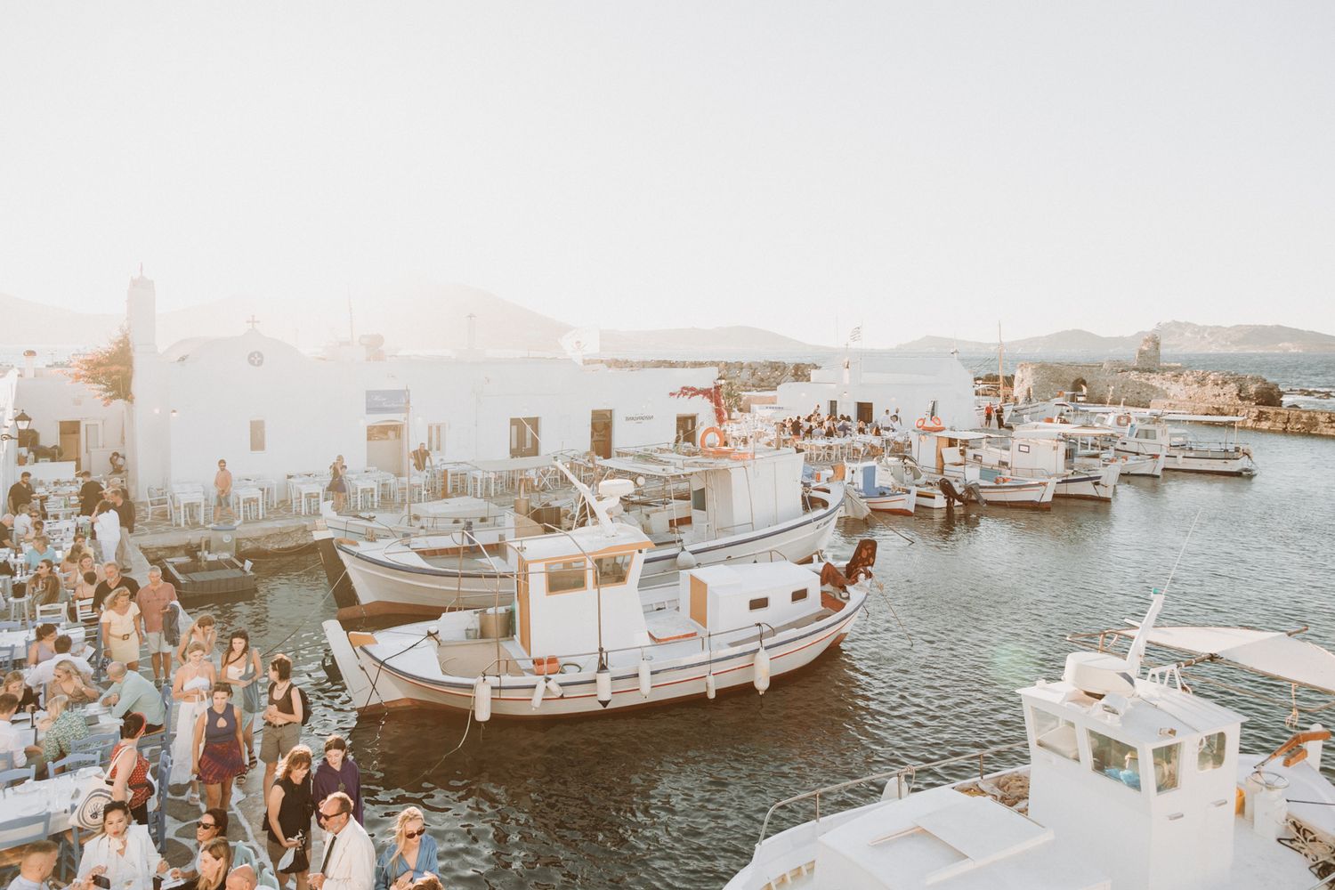 Scenic harbor view with white boats and Mediterranean architecture in soft evening light.