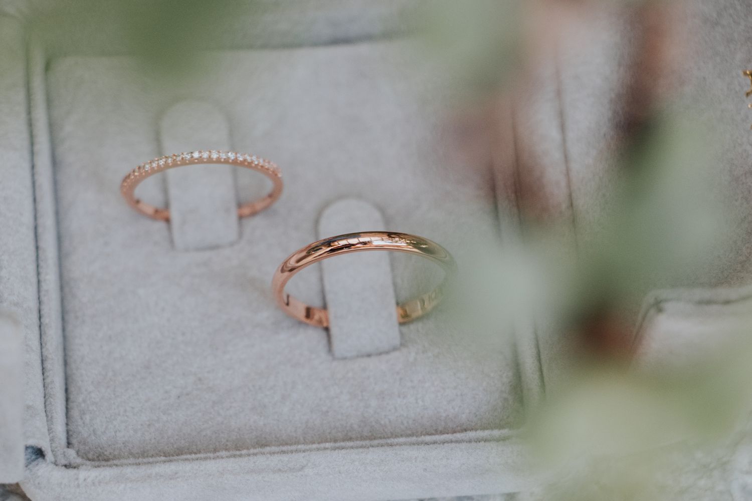 Two delicate rose gold rings with white rectangular stones displayed on a soft gray surface.