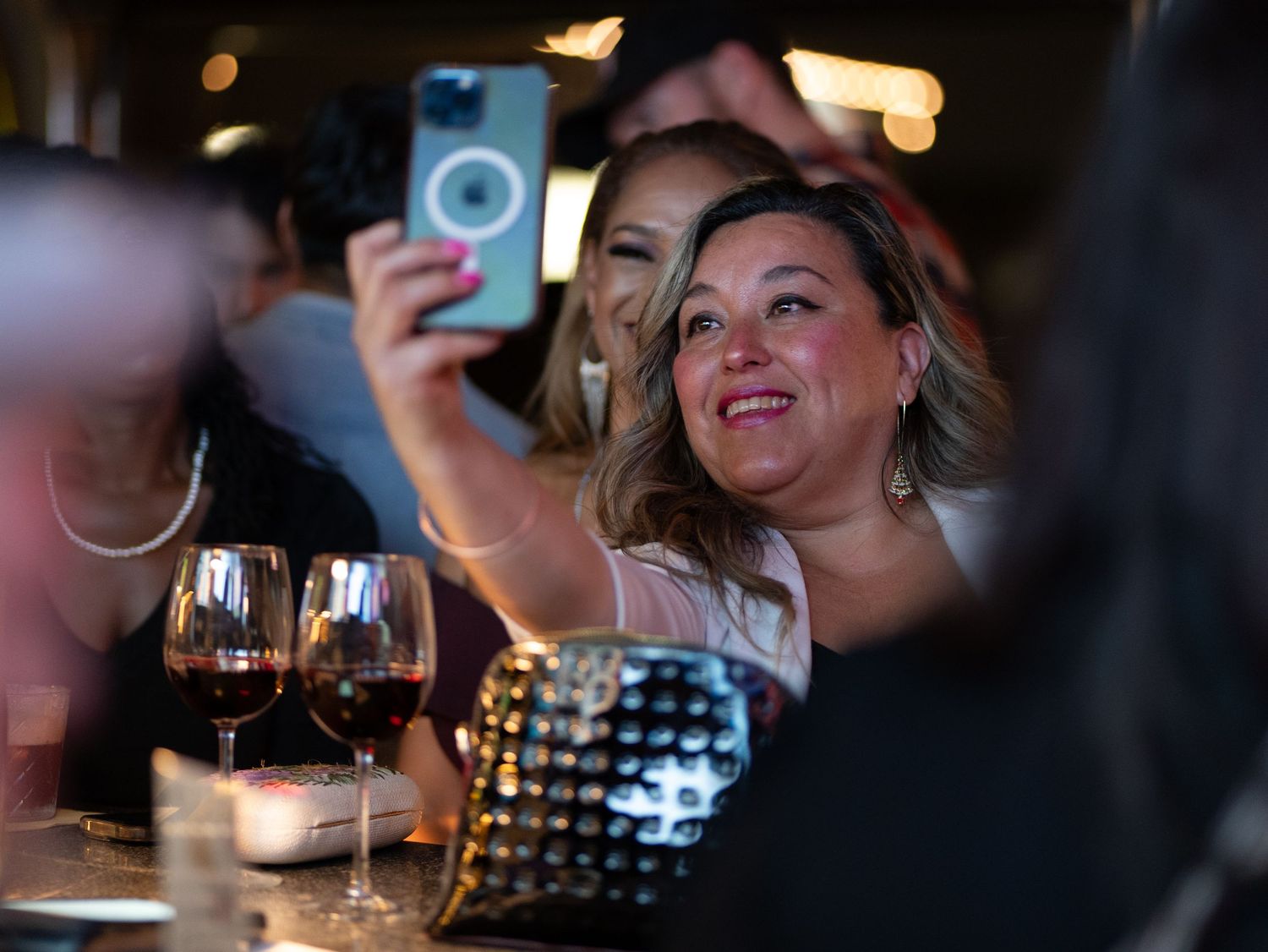 People enjoying wine and conversation at a dimly lit restaurant with glasses clinking and laughter.