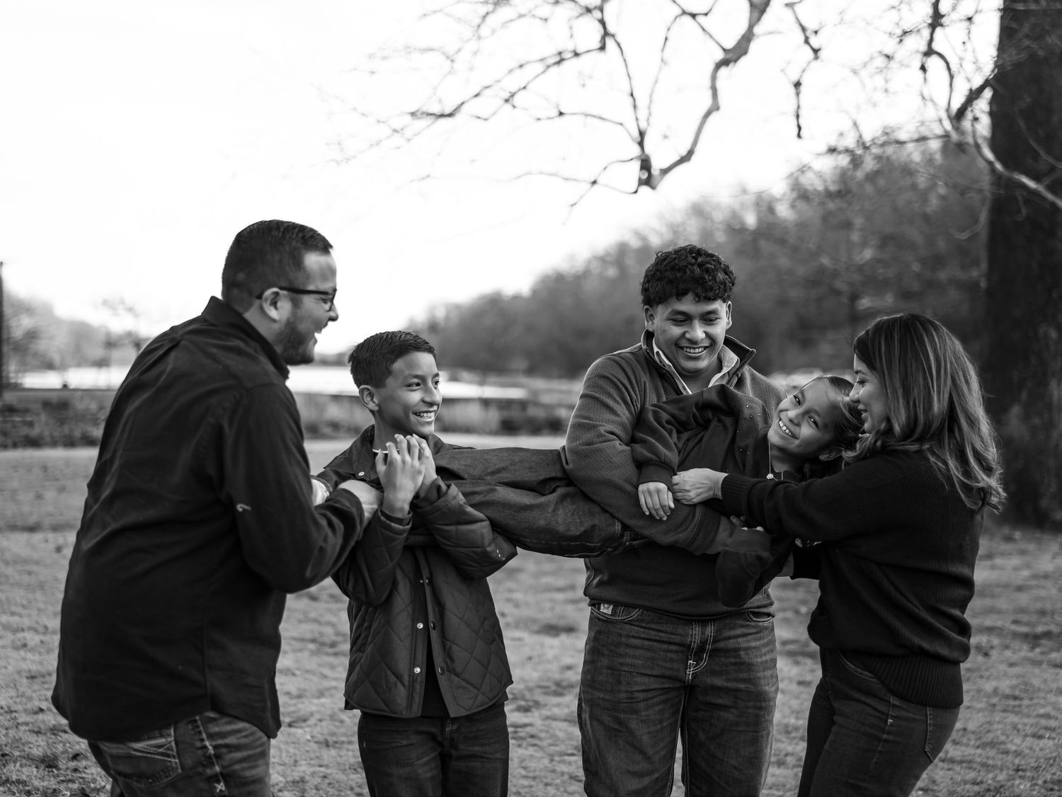 Black and white sequence of people playing football in a field showing progression of a tackle and fall.