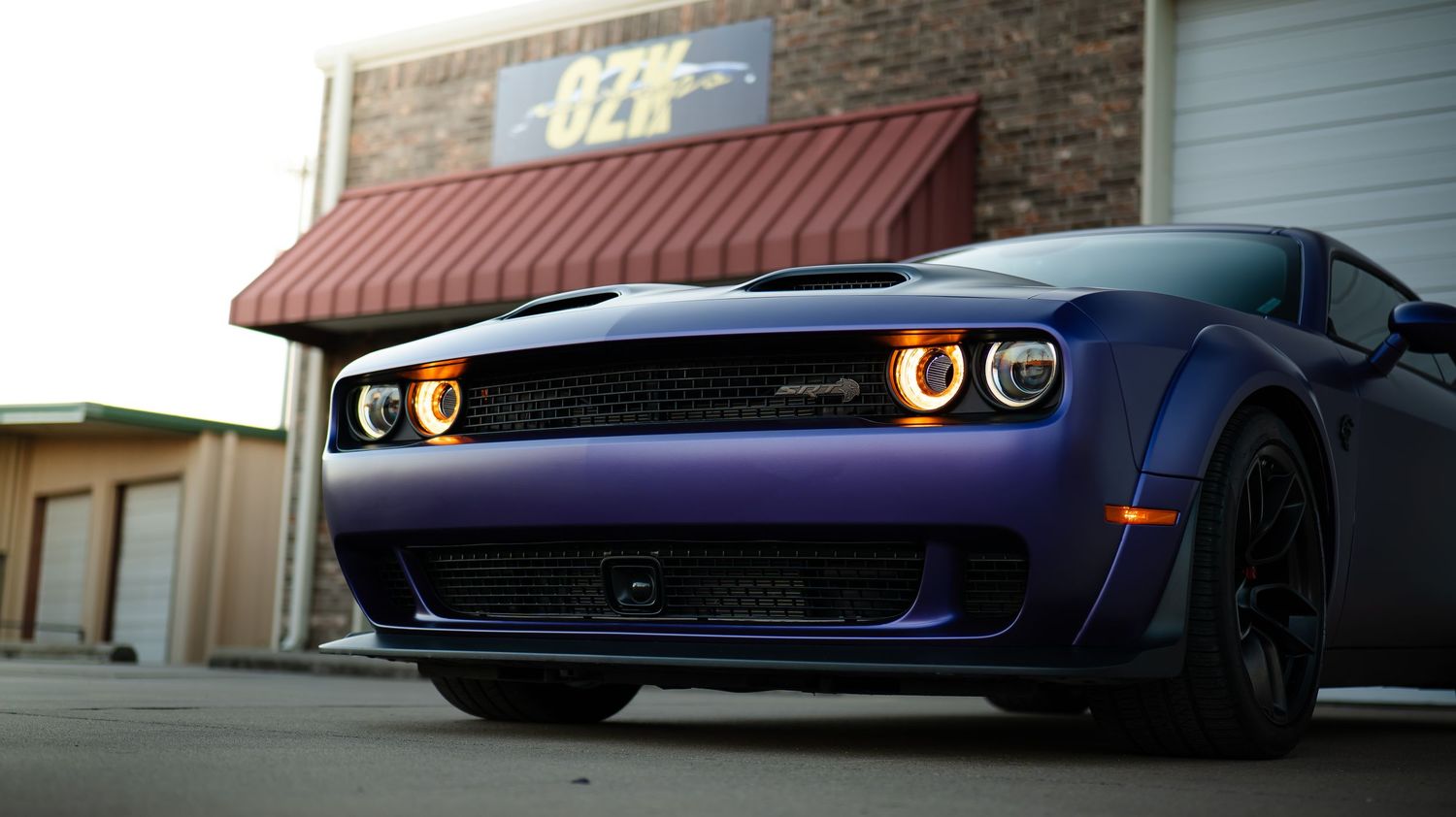 Dark blue sports car with illuminated headlights parked in a showroom setting.