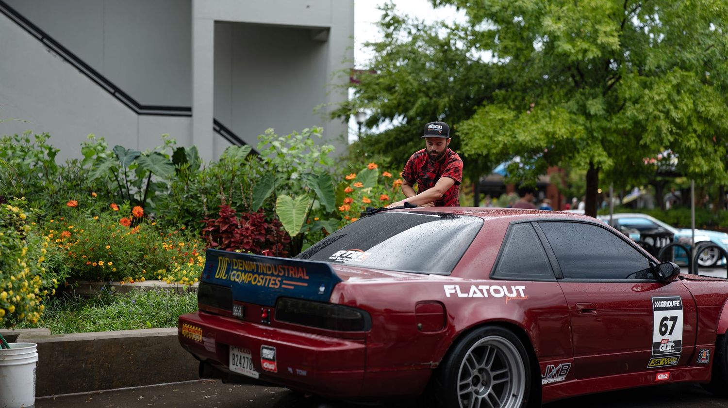 Modified sports cars parked at a car show with colorful graffiti murals in the background.