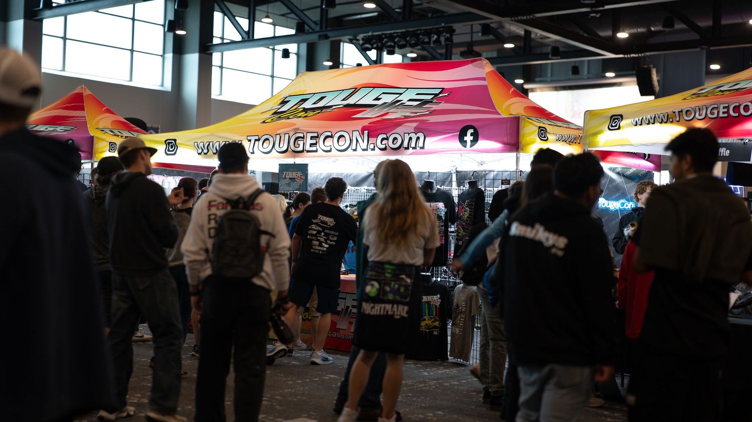 Indoor event space with cars and people gathered under dark ceiling lighting.