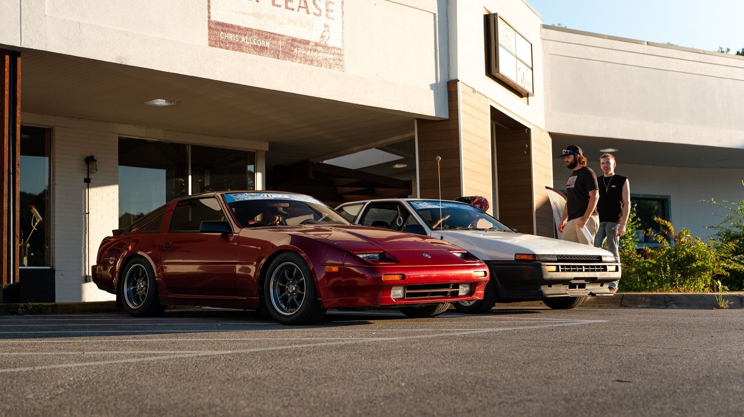 Row of classic and modern sports cars displayed outside a commercial building.