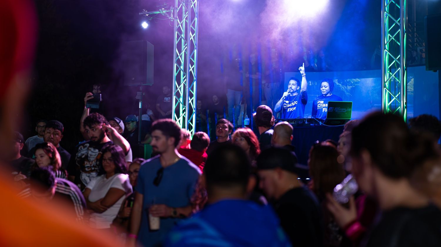 Stage lighting and truss system illuminated in purple and blue at an indoor venue.