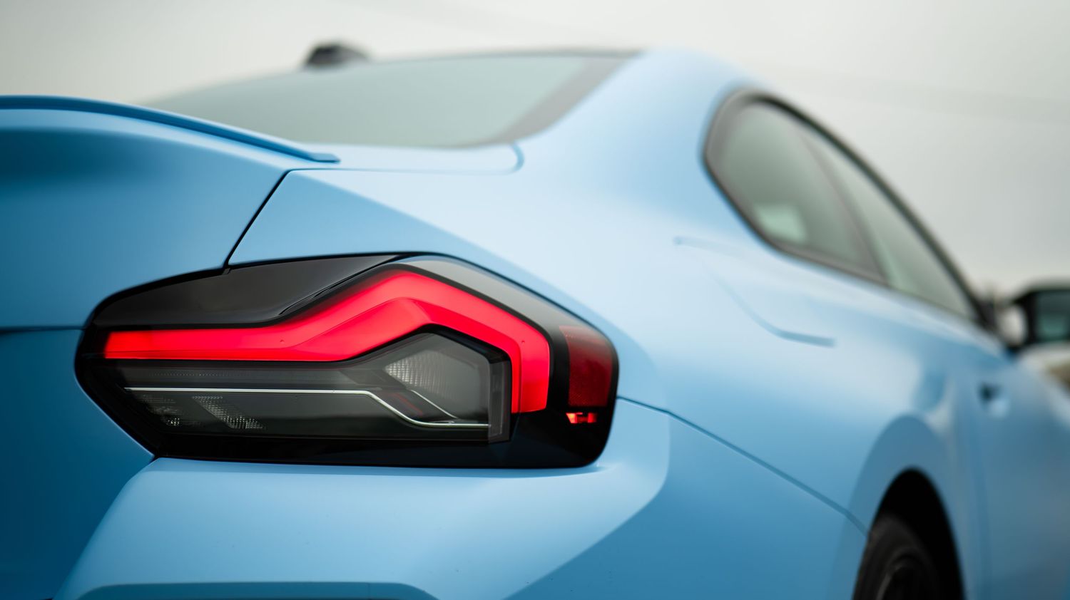Detailed exterior shots of a light blue BMW M2's body panels and lights.