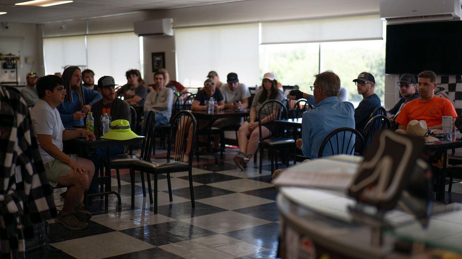 Interior view of cafeteria space with scattered groups of people at tables.