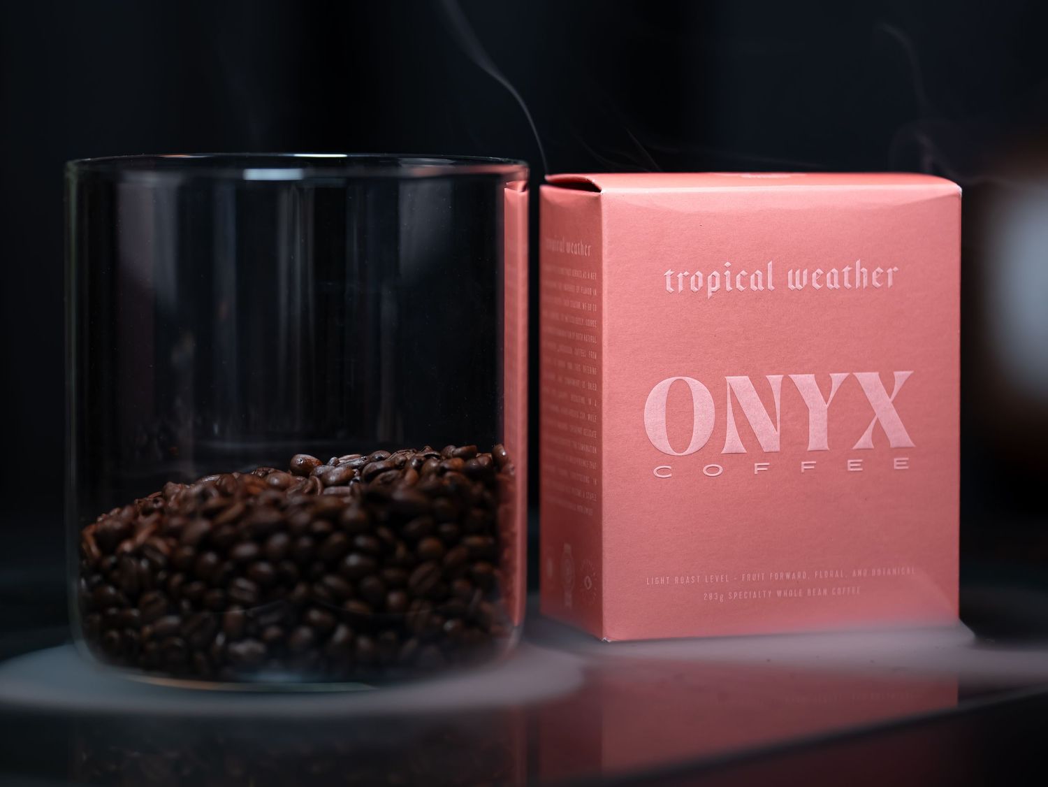 Onyx Coffee Lab Tropical Weather blend in a glass jar beside its pink packaging box.