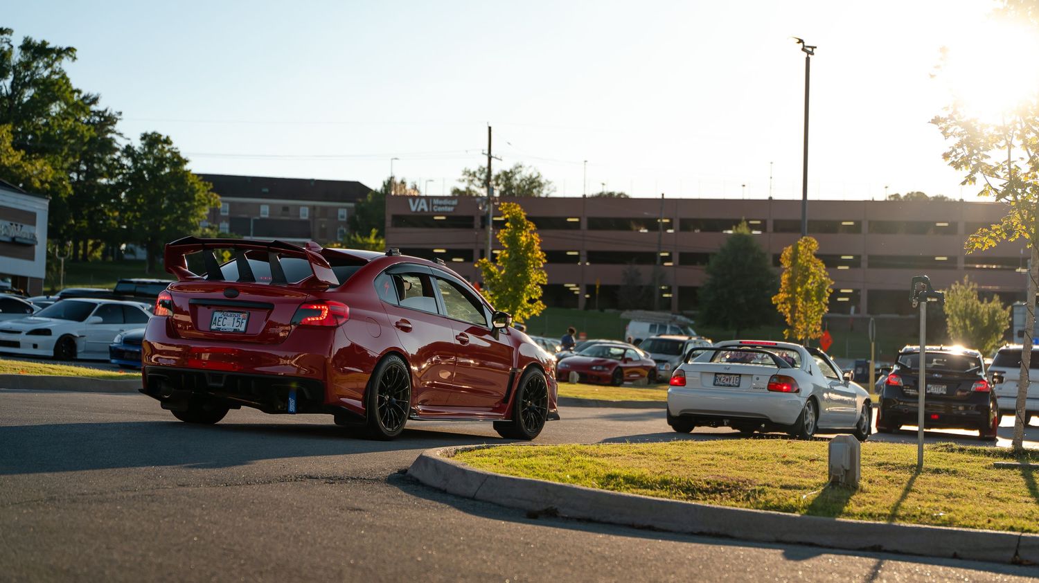 Panoramic view of cars parked at an auto show during sunset.