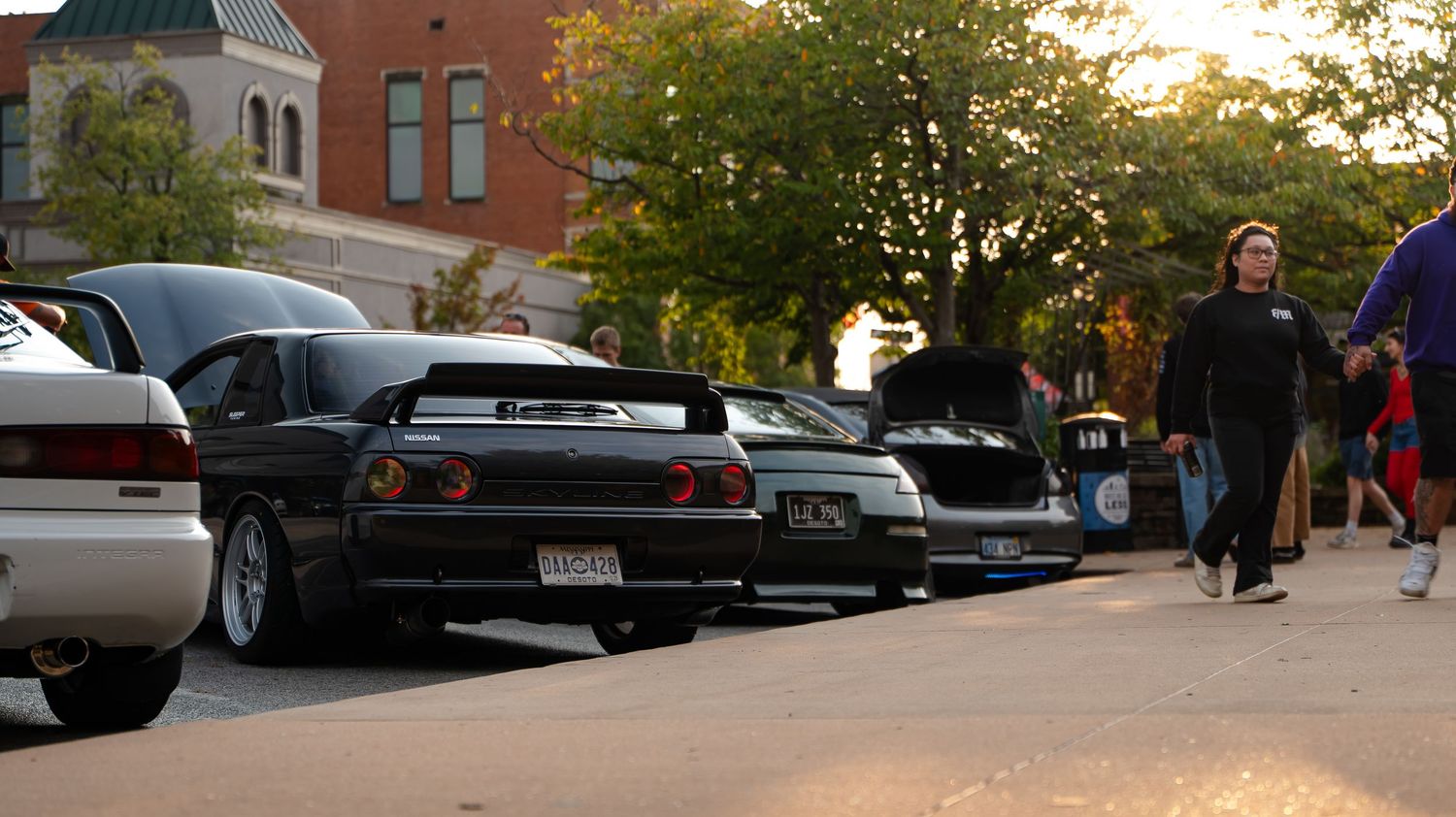 Street scene with brick buildings and parked vehicles at golden hour.