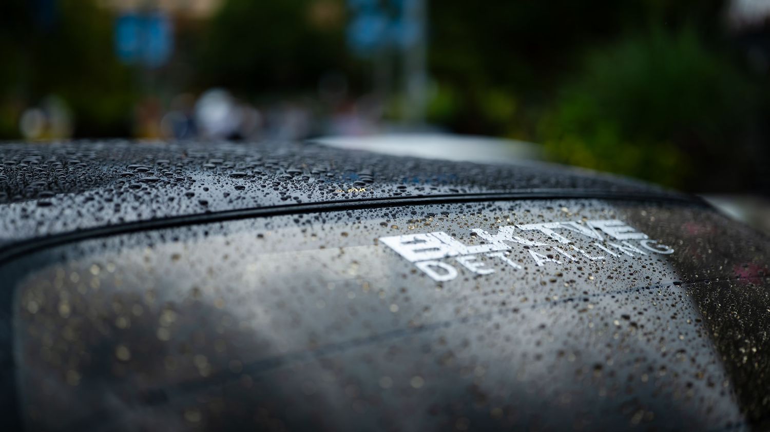 Close-up of water droplets on a dark automotive surface.