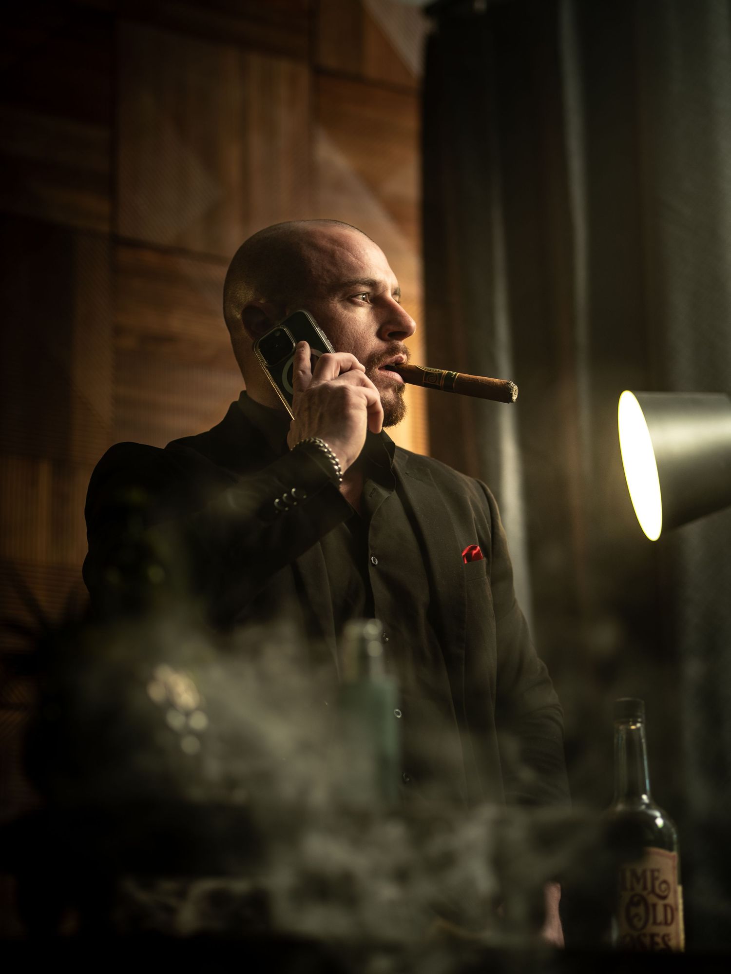 A performer in dark attire sings passionately into a microphone on a dimly lit stage with atmospheric smoke effects.