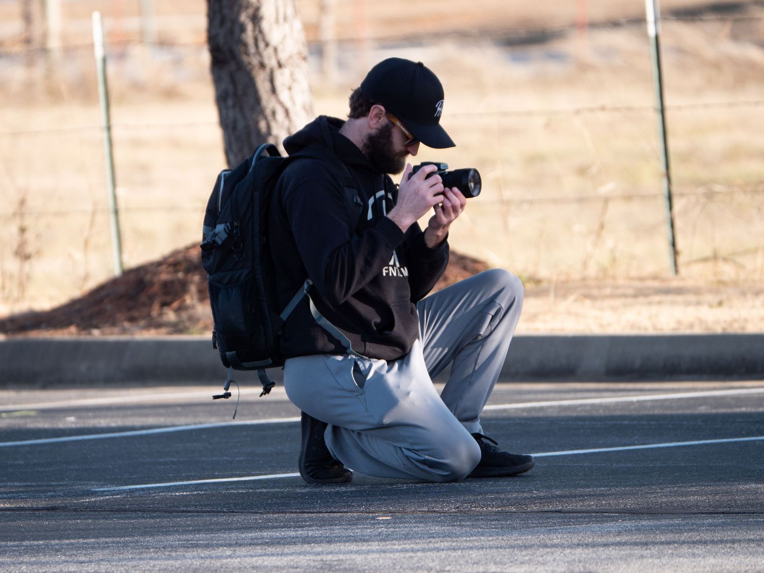 A photographer crouching low to take photos on a concrete surface.