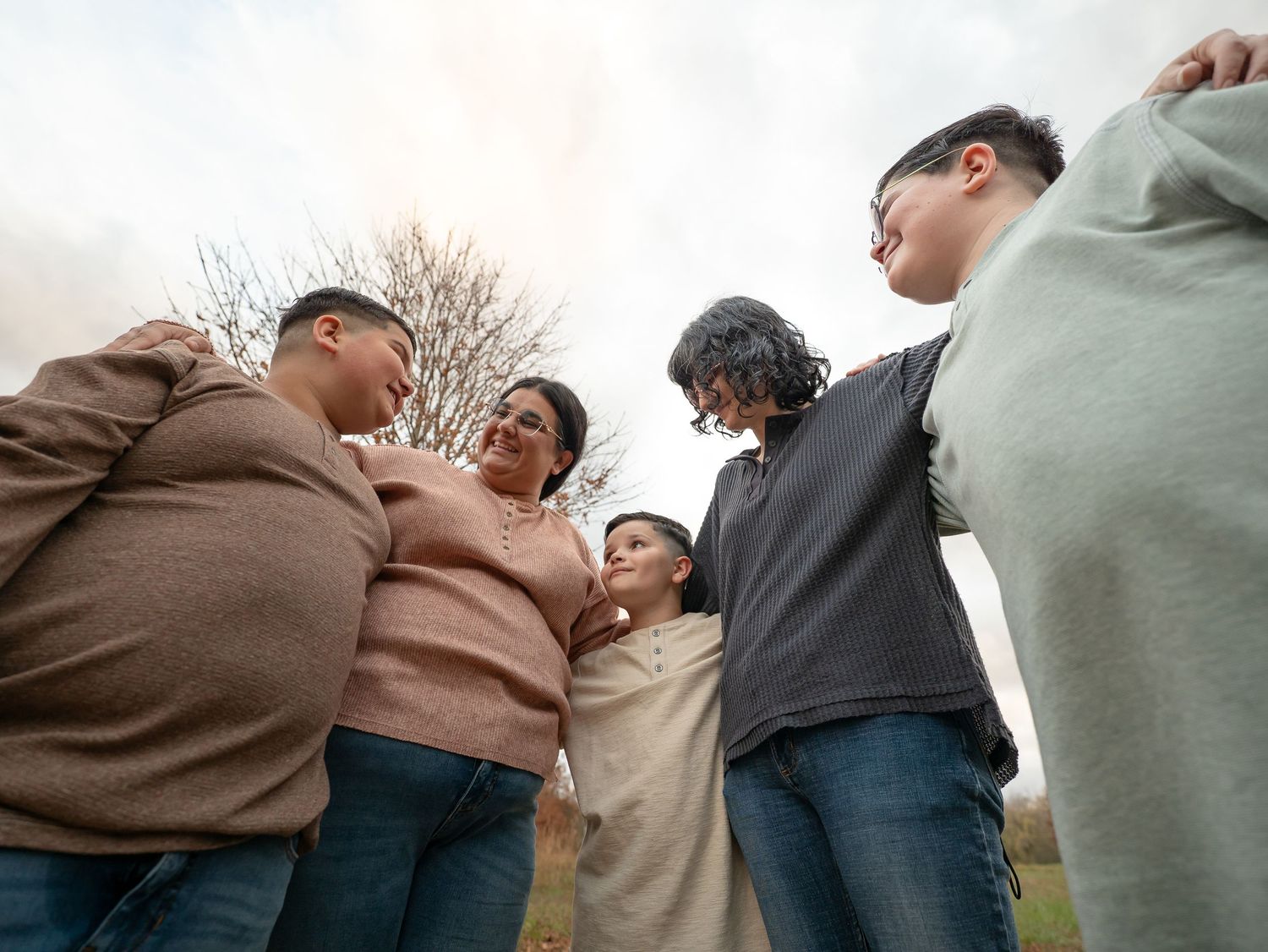 A group of people huddle together in a circle formation outdoors during autumn.