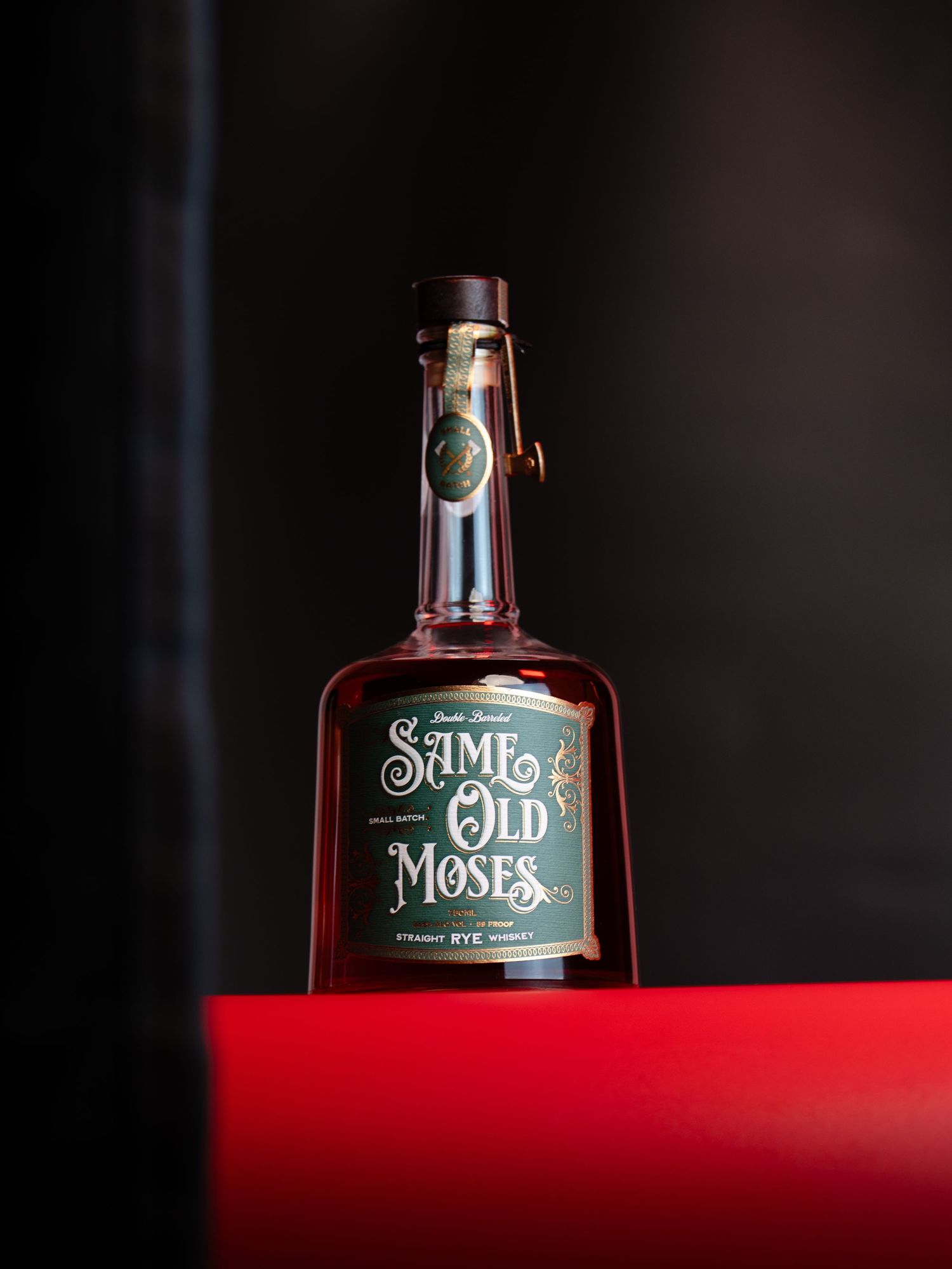 A bottle of Old Moses whiskey photographed against a dark background with dramatic red lighting.