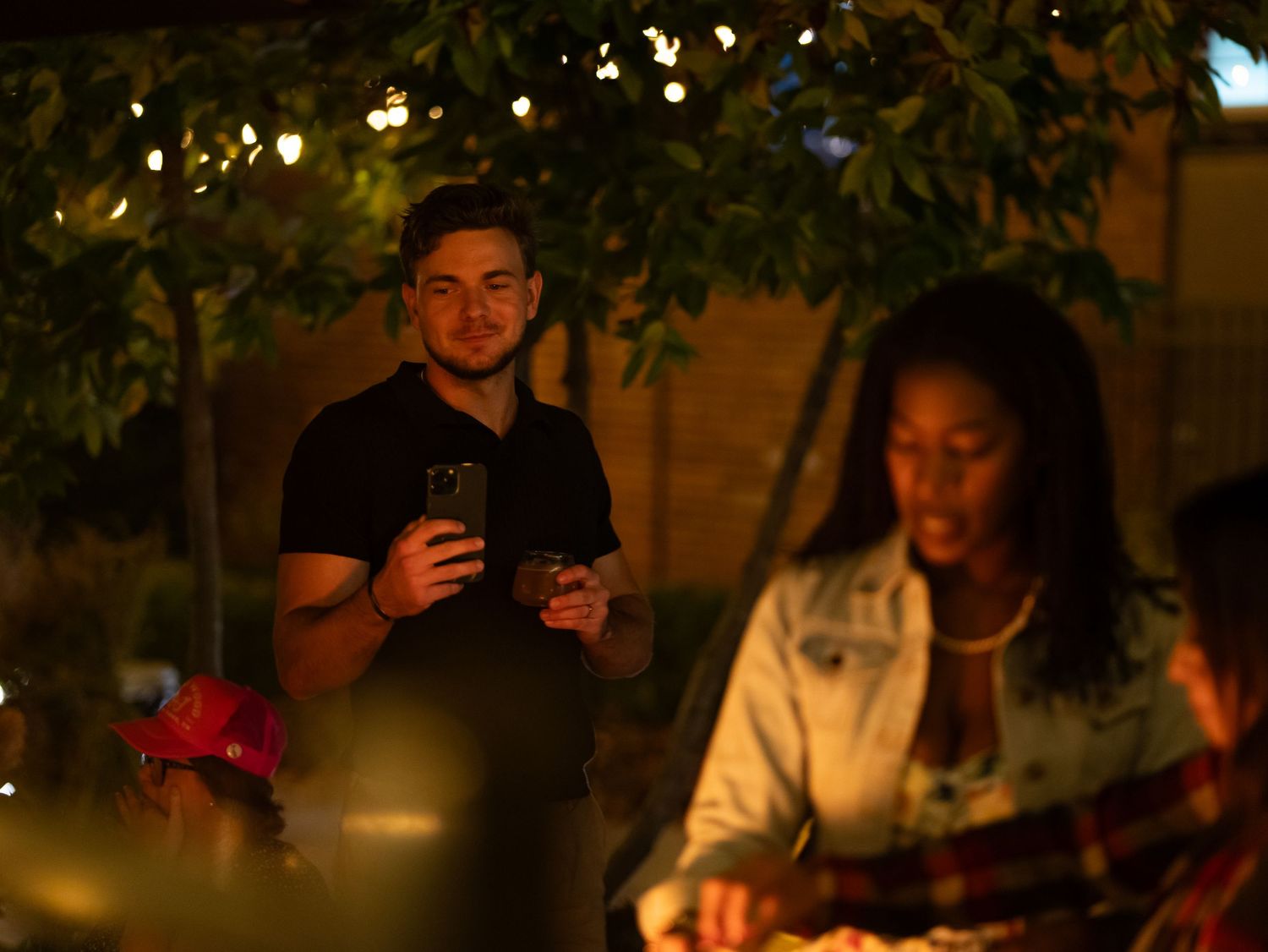 People gather for an evening outdoor dinner under string lights creating a warm, intimate ambiance.