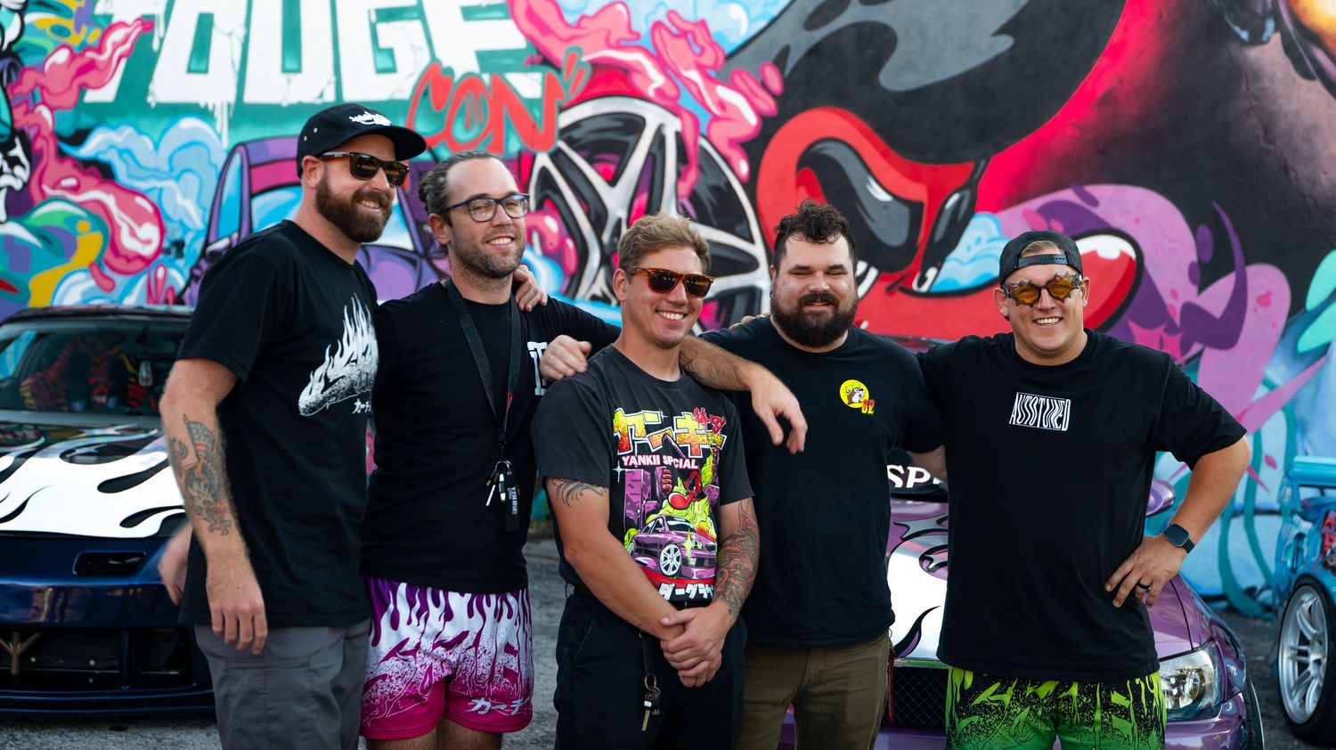 Colorful graffiti art wall serving as backdrop for a car show event.