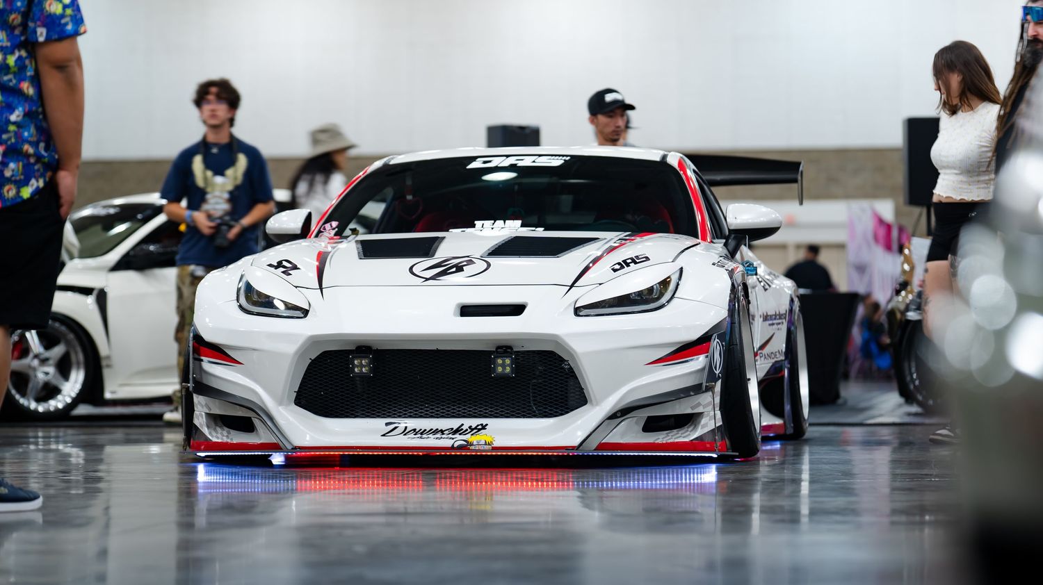 Custom performance vehicles lined up at an indoor automotive exhibition.