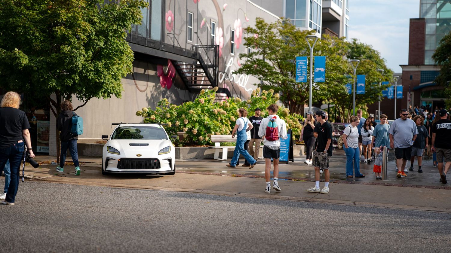 Panoramic view of an urban street with pedestrians and storefronts.