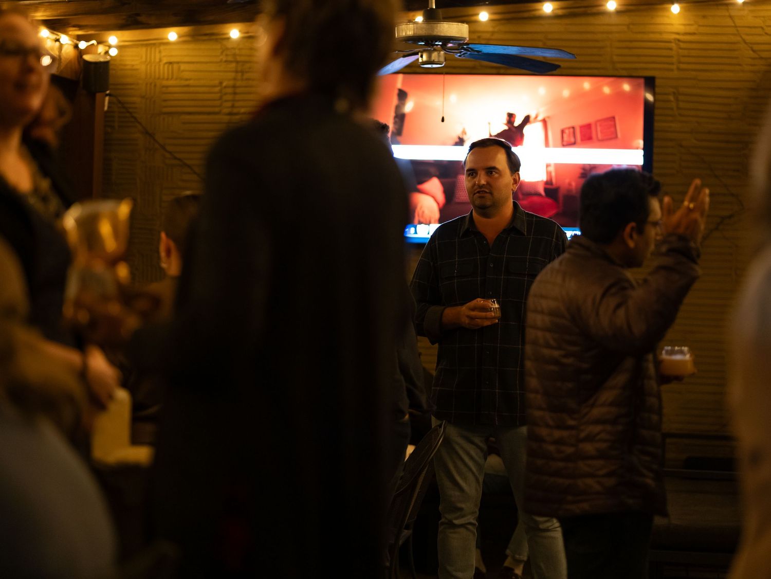 People enjoying drinks and conversation in a dimly lit bar with warm ambient lighting.