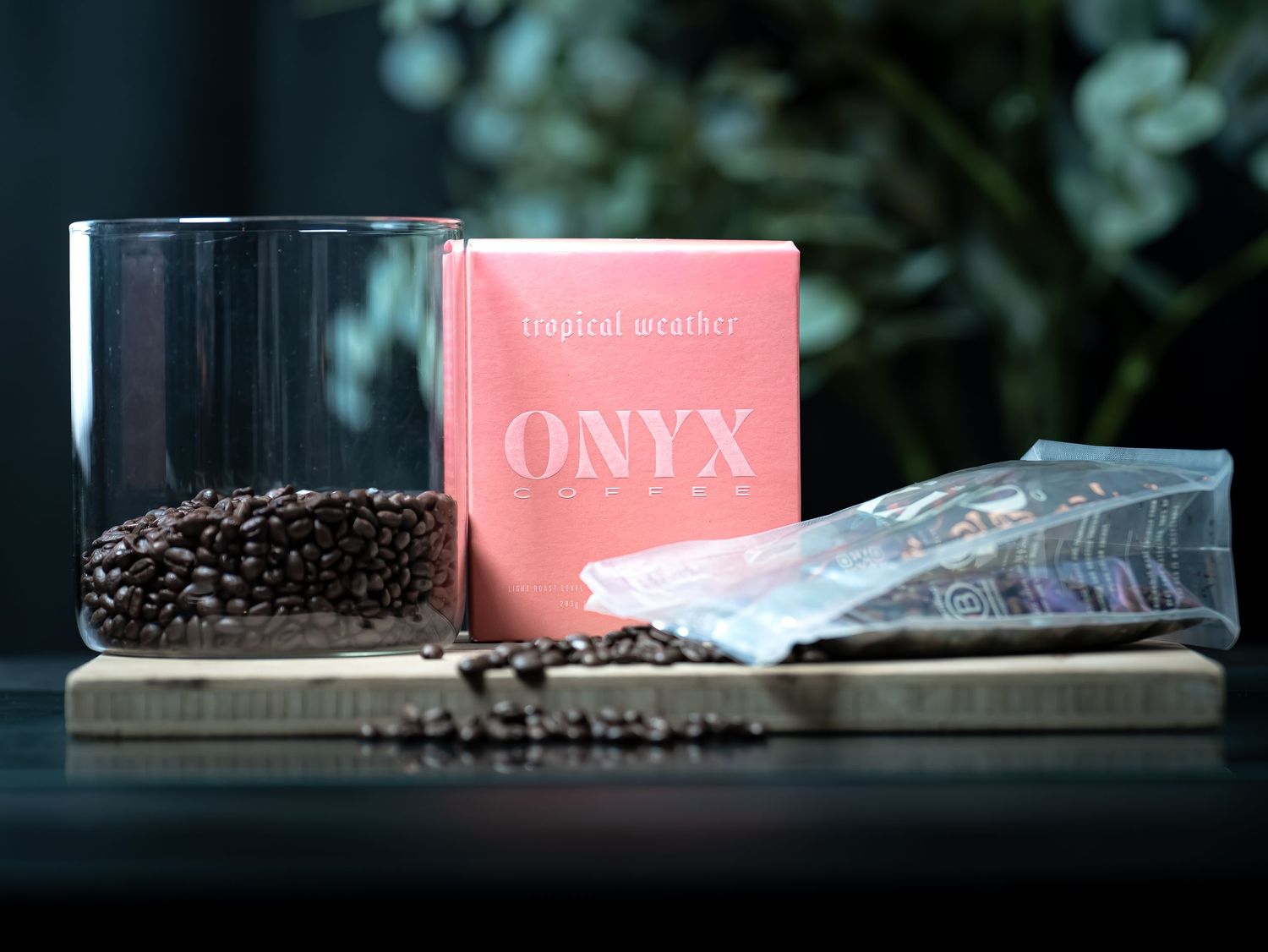 Onyx Coffee Lab tropical paradise roast box with glass jar of dark coffee beans on wooden board.