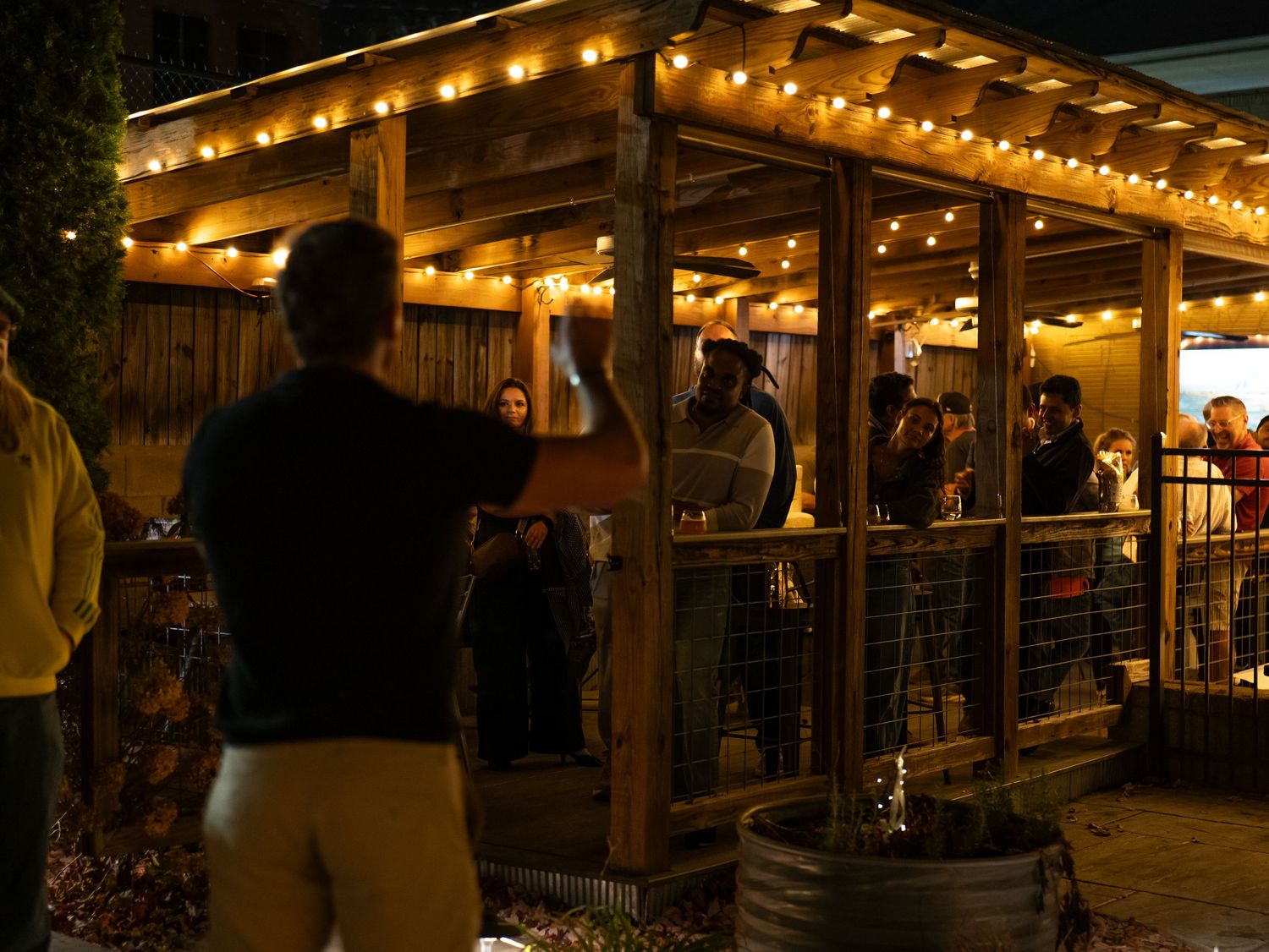 String lights illuminate a rustic wooden porch and deck area at night creating a warm, inviting outdoor ambiance.
