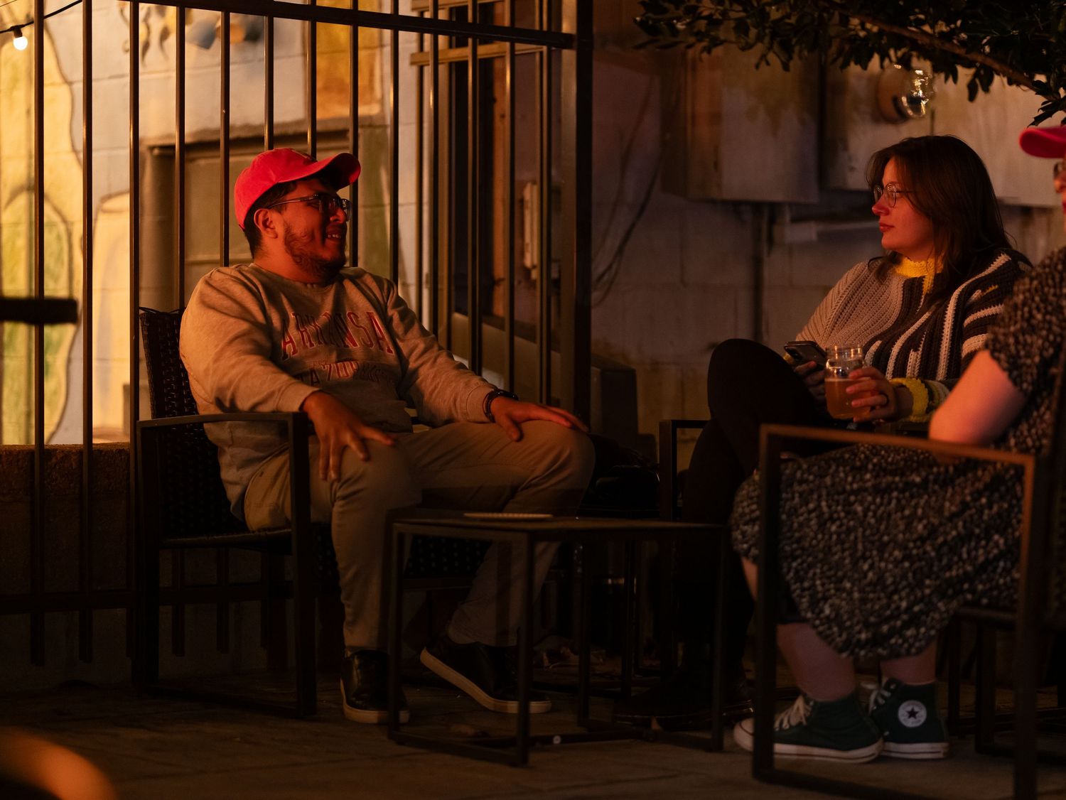 People sit in rocking chairs on a dimly lit porch at night creating a cozy, relaxing atmosphere.