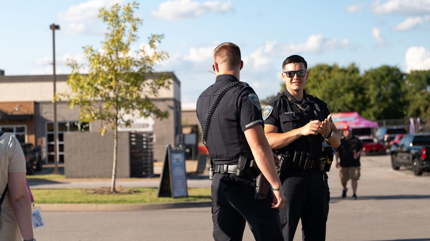 Law enforcement officers standing in parking lot during daytime event.