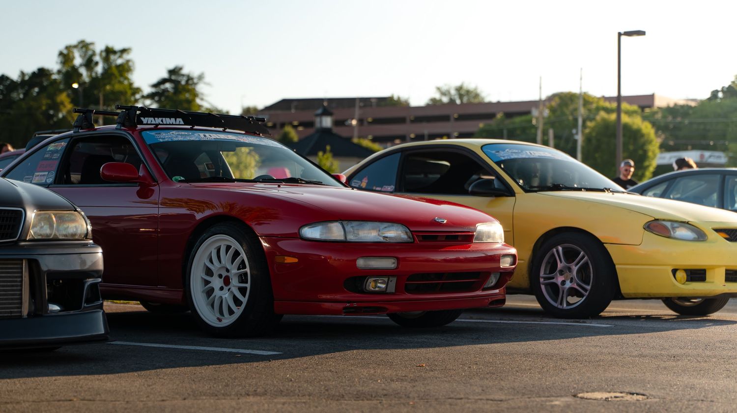 Wide shot of sports cars parked in a lot during sunset.
