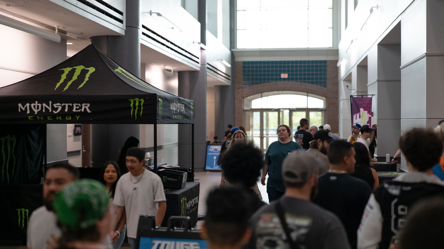 Interior hallway of a convention center with crowds of people walking through.