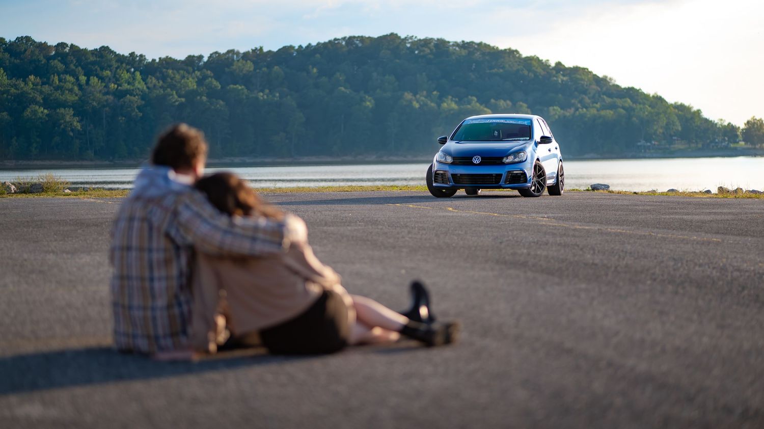 Panoramic view of a mountain landscape with a car parked on a paved area.