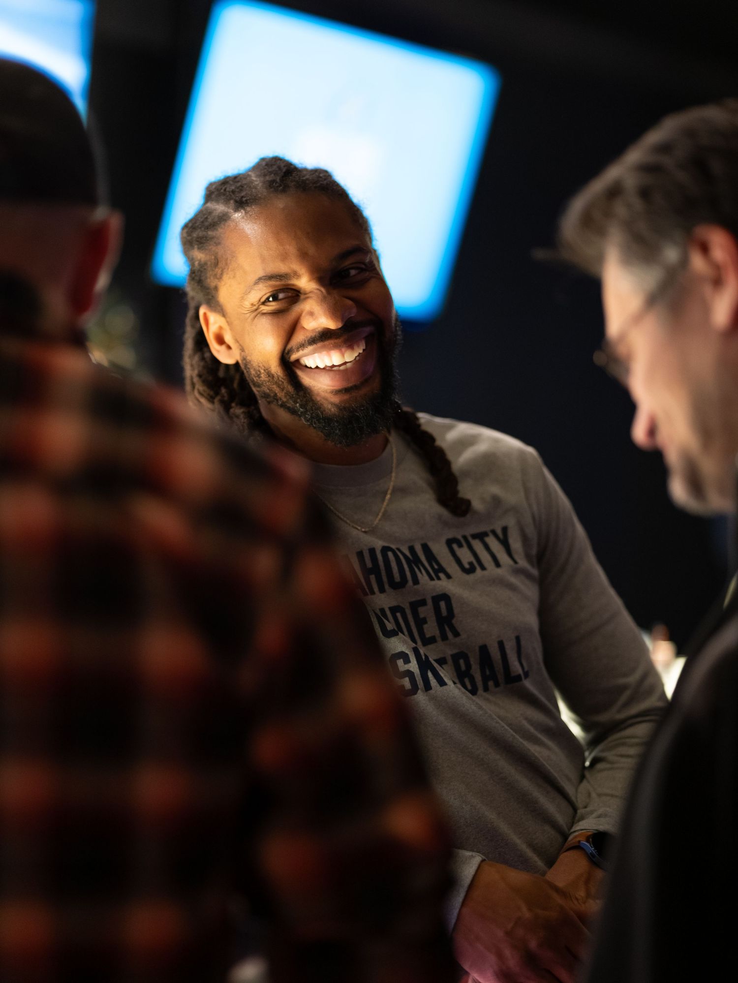 NBA player wearing a grey Brooklyn Nets sweatshirt smiles during an interview.