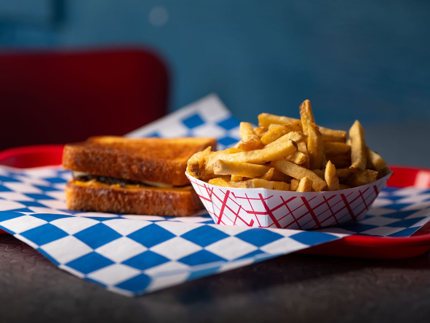 A panoramic food photo series showing french fries and sandwiches on blue and white checkered diner paper.