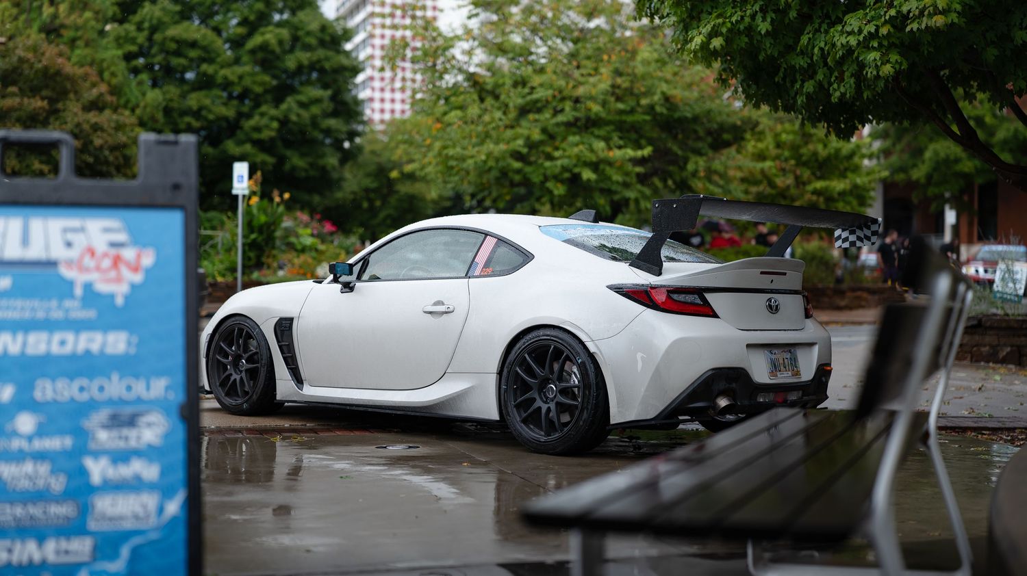 Modern sports cars parked in a row with lush green trees in the background.
