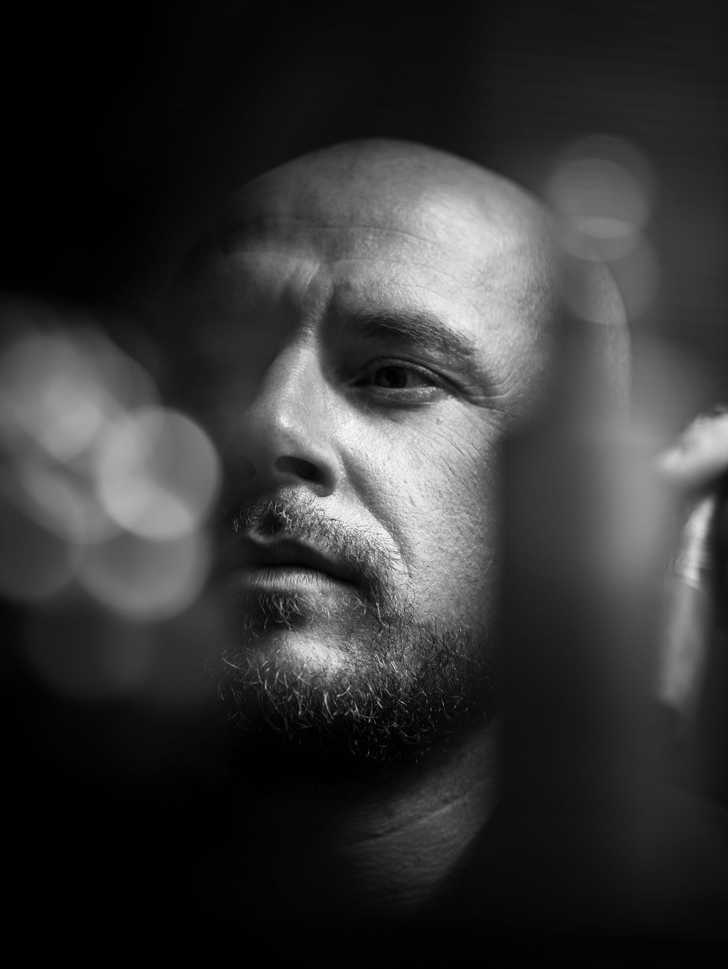 Moody black and white close-up portrait with bokeh lights in the background.