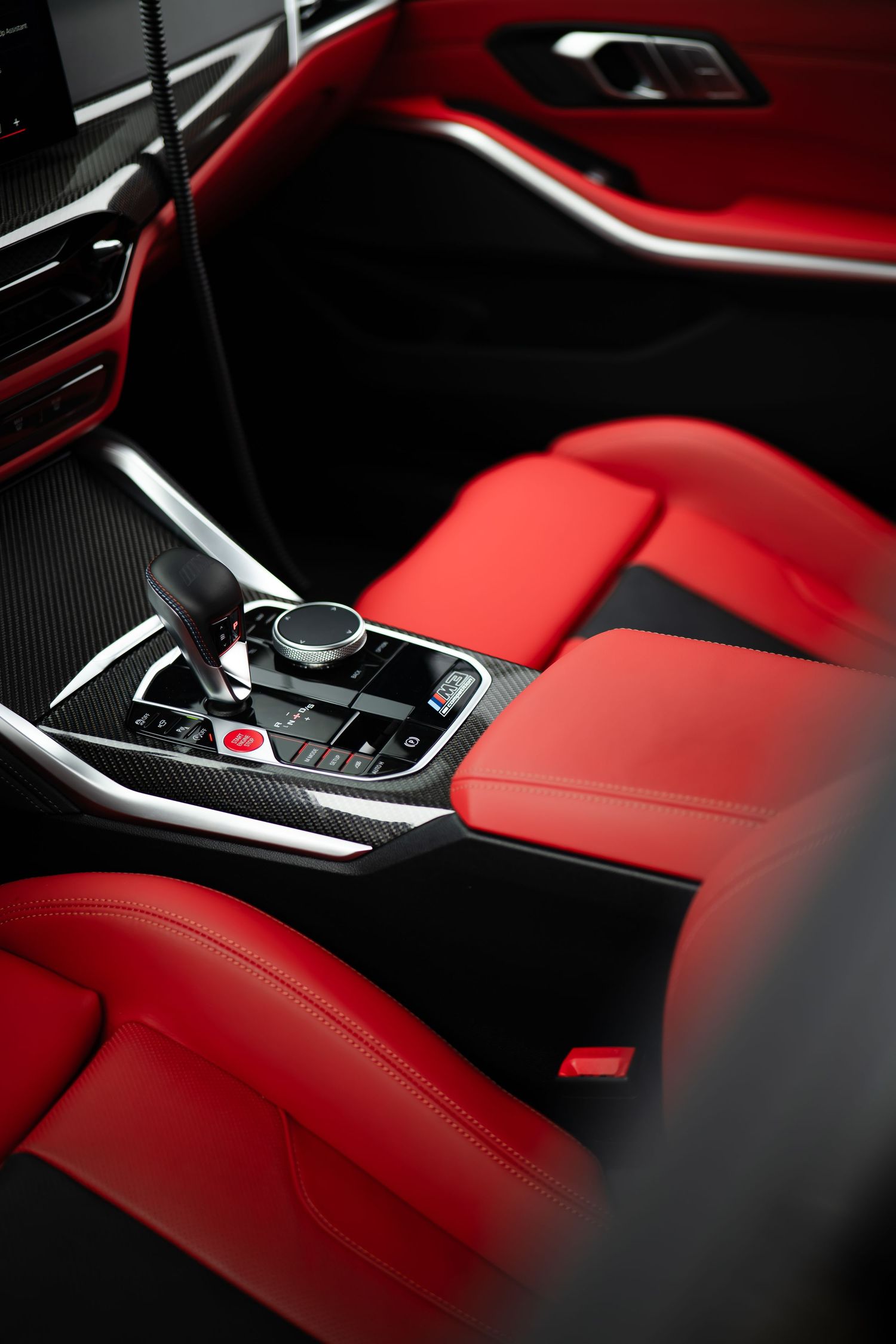 Luxury car interior with red leather seats, black carbon fiber trim, and automatic gear shift console.