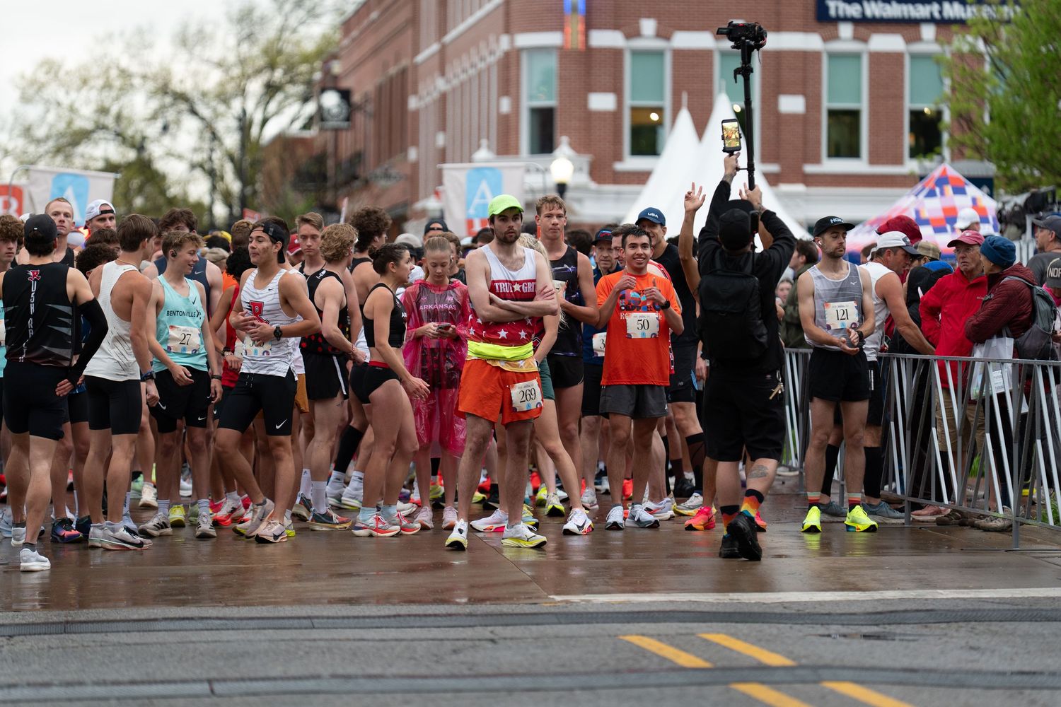 Runners gather at the starting line of a road race on a wet street near the Walmart Museum in Bentonville, Arkansas.