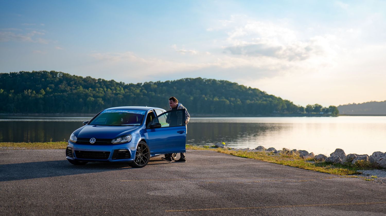 Wide landscape shot of sports cars against a mountainous backdrop at dusk.