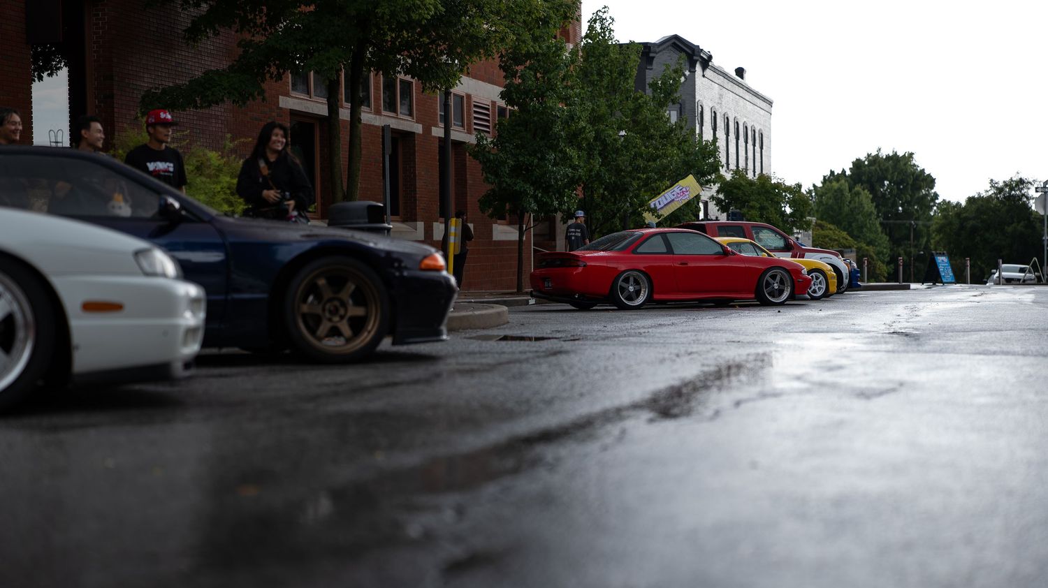 A panoramic view of a parking lot with cars on a rainy day.