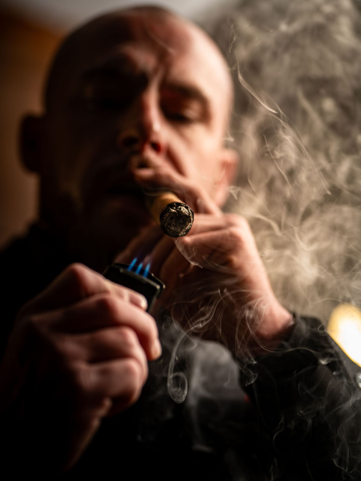 A series of moody photographs showing someone exhaling smoke in dramatic lighting against a dark background.
