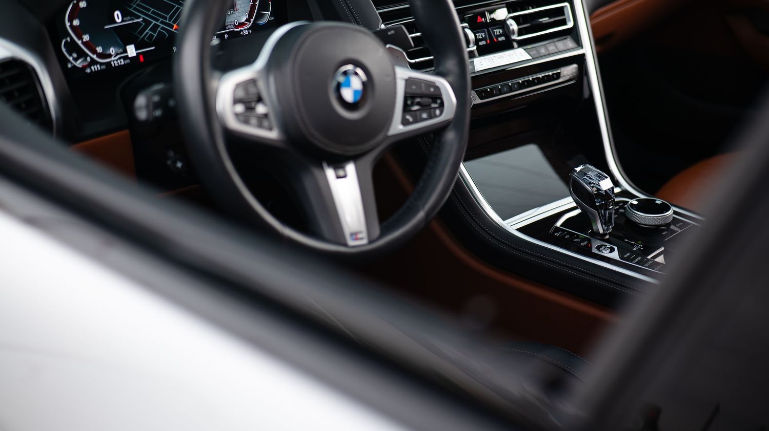 Close-up detail of a luxury BMW car interior showing brown leather and modern controls.