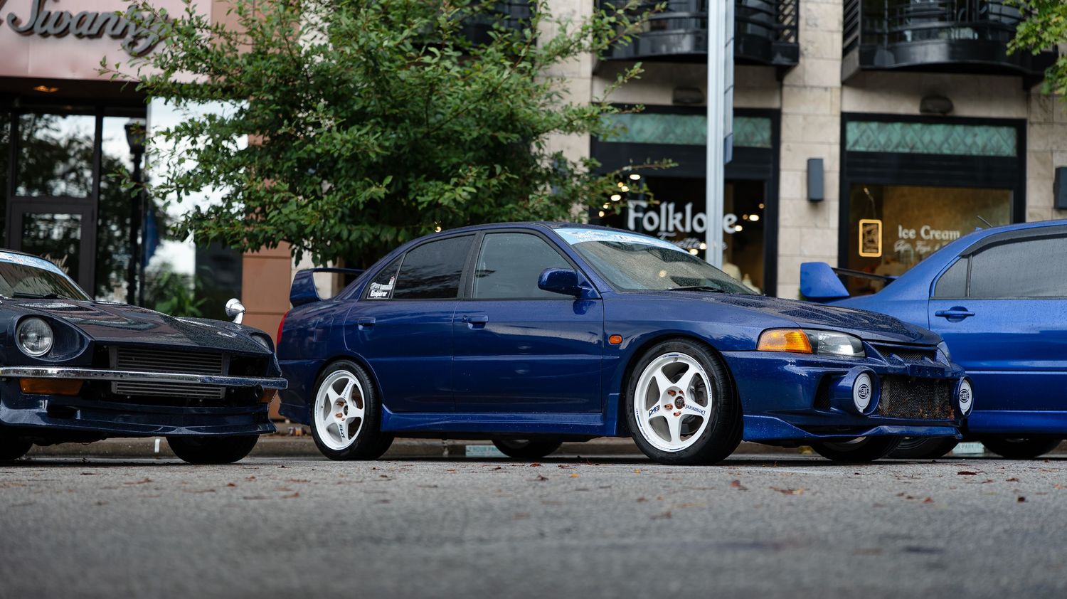 Line of blue sports cars parked in formation at a car show.