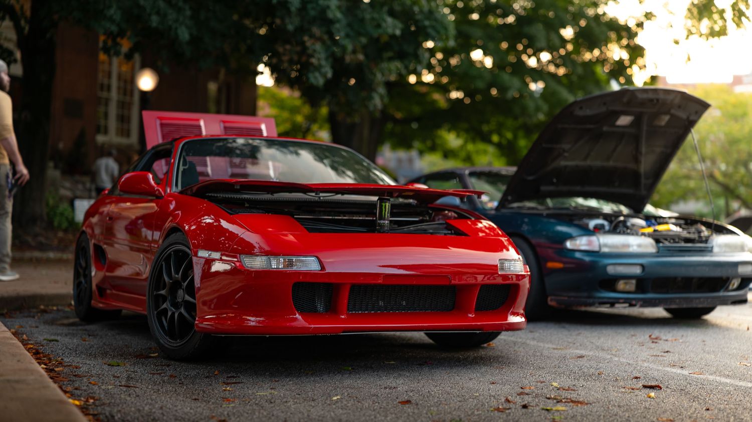 Custom lowered sports cars displayed at an outdoor automotive gathering.