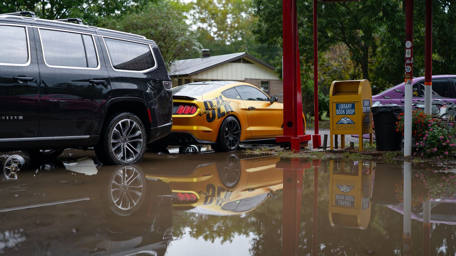 Modified vehicles lined up in a flooded parking area with standing water reflections.
