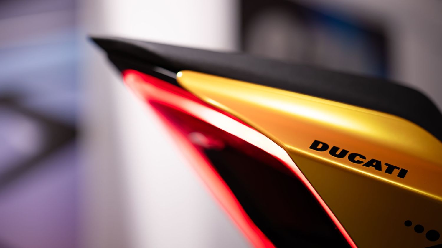 Close-up detail shot of a yellow Ducati motorcycle fairing in dramatic lighting.