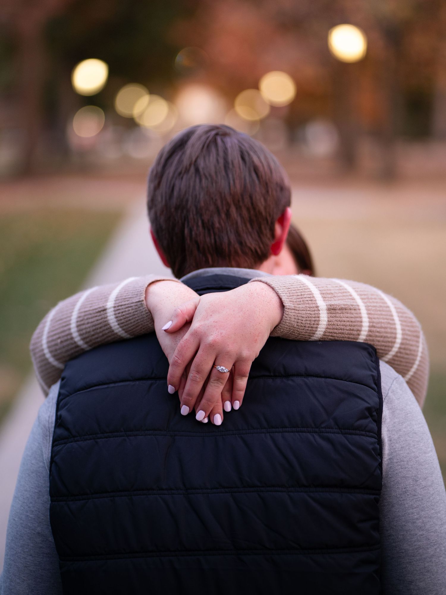 A couple embraces in a romantic moment with soft bokeh lights in the background at sunset.