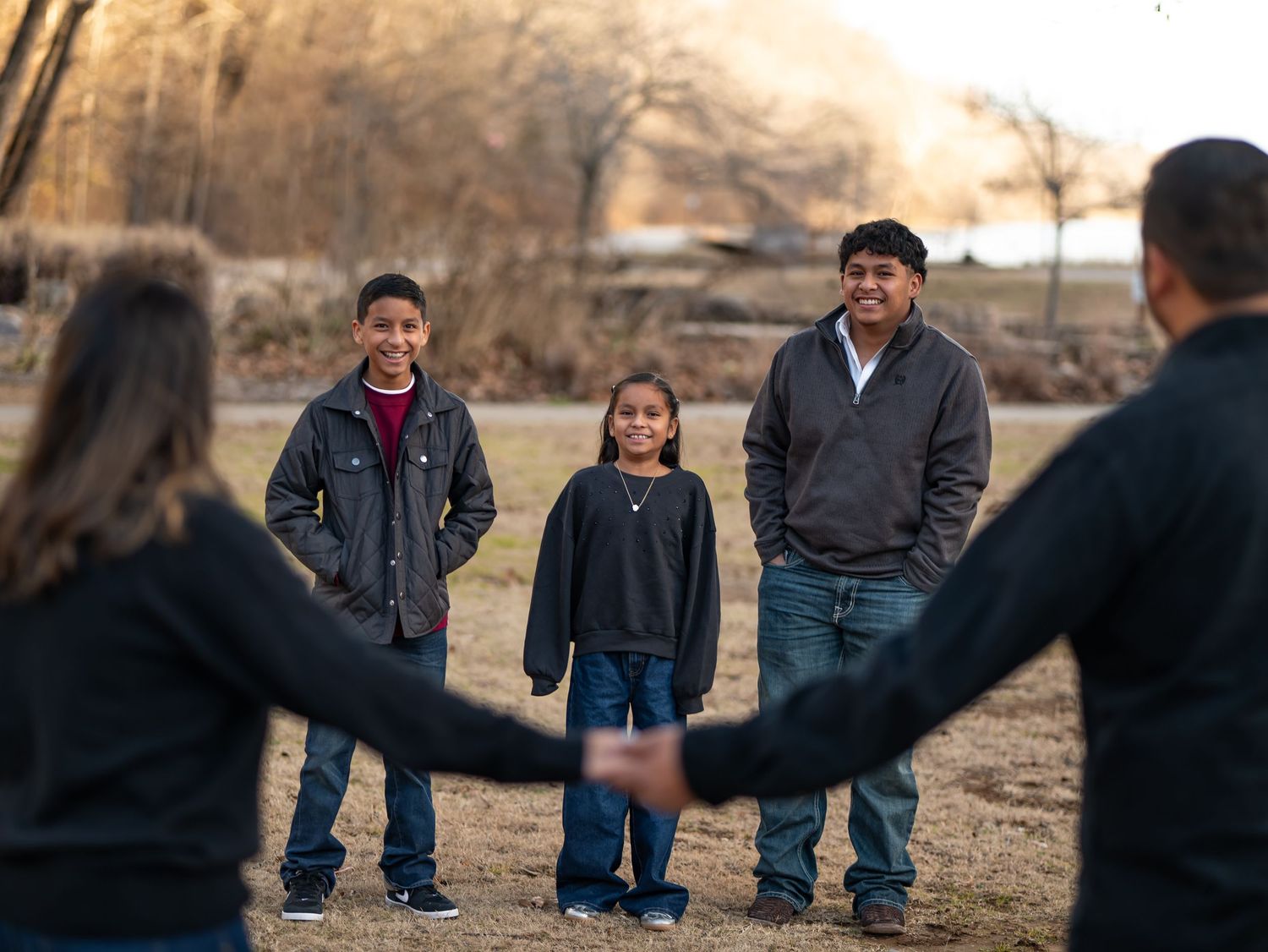 People's feet walking in a line on dirt ground during a group activity outdoors.