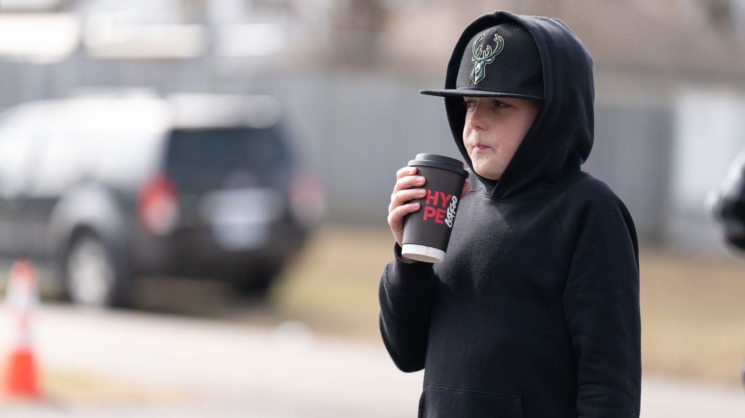 Hands holding disposable coffee cups against a blurred background.