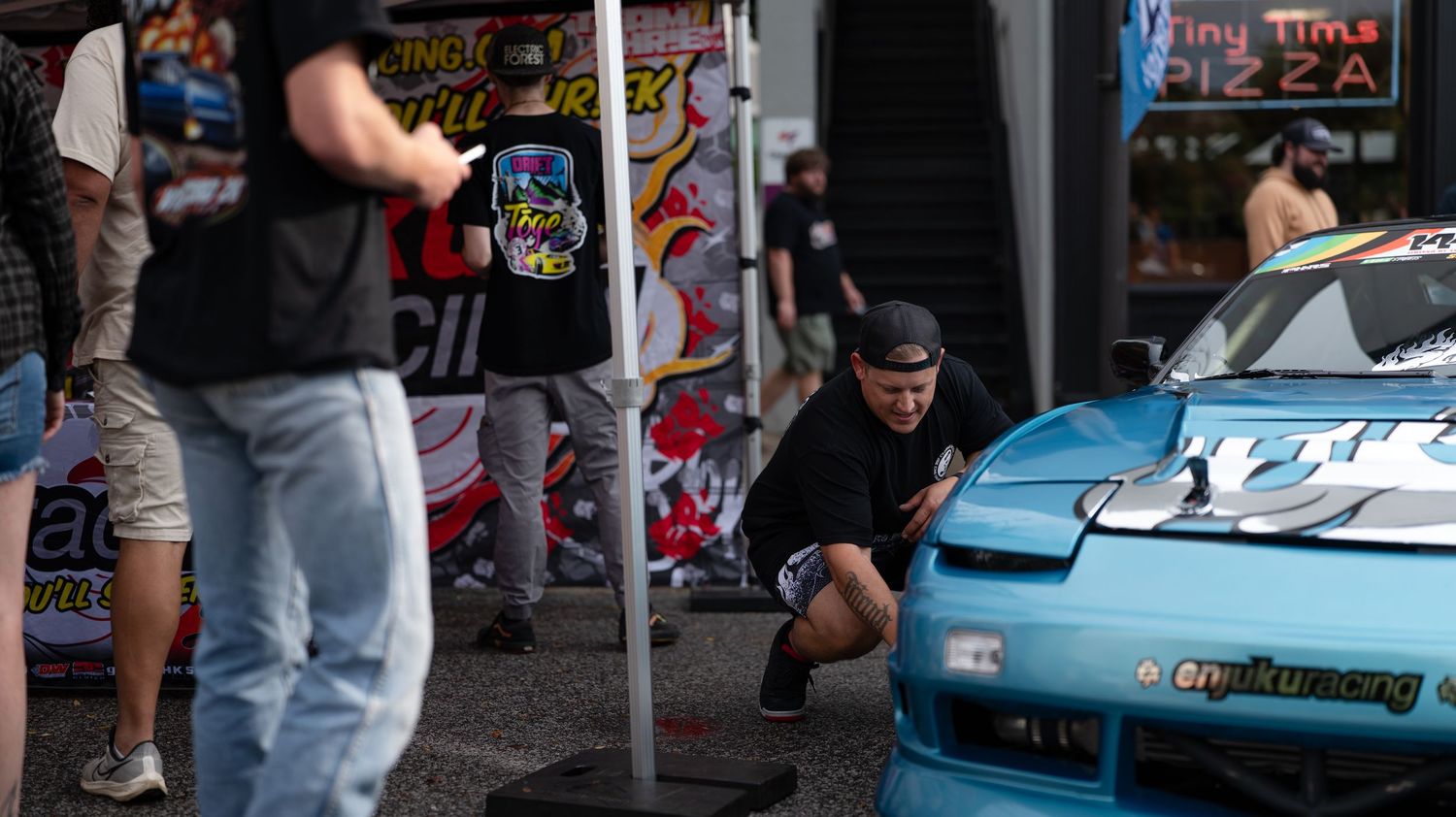 Cars lined up at an outdoor auto show featuring modified vehicles and custom paint jobs.